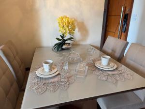a table with glasses and a vase of yellow flowers at Apartamento Serra Espírito Santo in Serra