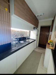 a kitchen with white cabinets and a black counter top at Apartamento Serra Espírito Santo in Serra +21 photos