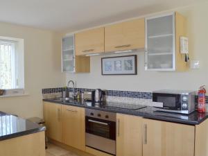 a kitchen with wooden cabinets and a sink and a microwave at Dewsnap Spring- Rtt4 in Chinley +10 photos