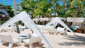 a group of white chairs and tables on the beach at Coral Beach Hotel Punta Cana in Punta Cana