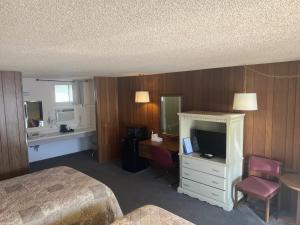 a hotel room with a bed and a desk and a television at El Portal Motel in Beatty