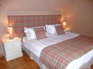 a bedroom with a bed and two night stands with lamps at Clochridgestone Cottage in Aberargie