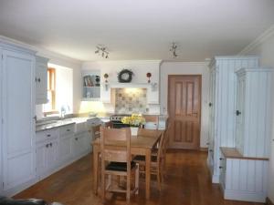 a kitchen with white cabinets and a wooden table at Clochridgestone Cottage in Aberargie