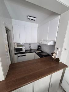 a kitchen with white cabinets and a wooden counter top at Appartement Esmeralda in Knokke-Heist +10 photos
