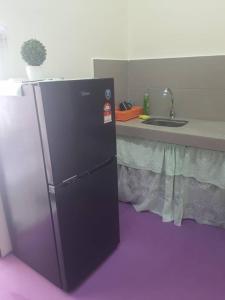 a black refrigerator in a kitchen with a sink at Lavender 8B Homestay in TanjongMalim