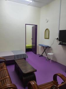 a room with purple carpet and a bed and a table at Lavender 8B Homestay in TanjongMalim