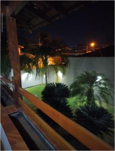 a fence with palm trees in a yard at night at Terraco Urbano Quarto Berlim in Sao Jose do Rio Preto