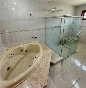 a bathroom with a tub and a glass shower at Terraco Urbano Quarto Berlim in Sao Jose do Rio Preto