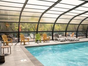 an indoor swimming pool with chairs and a conservatory at Appartement confortable avec cuisine équipée - API-1-52-759 in Granges-Aumontzey