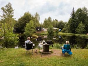 two people sitting in chairs in front of a pond at Appartement confortable avec cuisine équipée - API-1-52-759 in Granges-Aumontzey