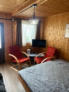 a bedroom with two chairs and a bed and a tv at The Orchard Manor in Ociu