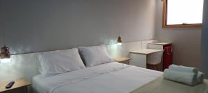 a bedroom with a bed with white sheets and a window at Riviera Sanary Praia, Conforto e Tranquilidade in Serra
