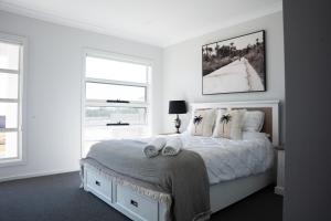 a white bedroom with a bed with two towels on it at Huntlee Haven Luxe in North Rothbury