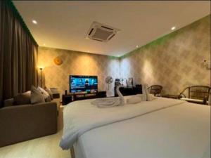 a bedroom with a large white bed and a television at Aika Homestay in Shah Alam