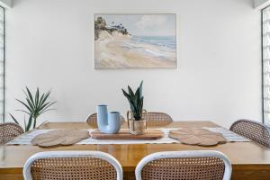 a dining room table with chairs and a painting on the wall at Alexandra on the Pacific in Mooloolaba