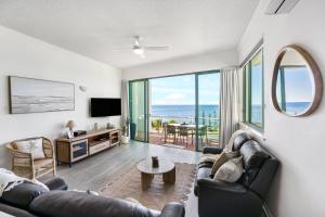 a living room with a couch and a tv at Alexandra on the Pacific in Mooloolaba
