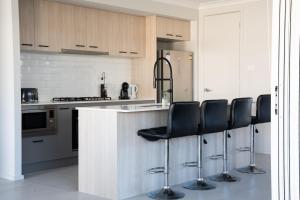 a kitchen with a counter with black chairs in it at Huntlee Haven Luxe in North Rothbury