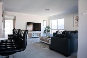 a living room with a couch and a tv at Huntlee Haven Luxe in North Rothbury