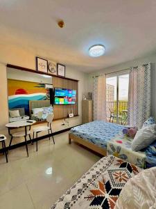 a bedroom with a bed and a desk and a tv at Saekyung Condominium in Suba