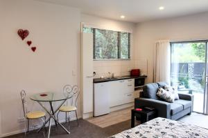 a kitchen and living room with a table and a chair at Amazing Kiwi Lodge in Whangamata