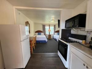 a kitchen with a refrigerator and a bedroom with a bed at Lakeside Motel in Moses Lake