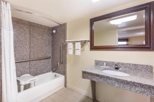 华纳罗宾斯Days Inn & Suites by Wyndham Warner Robins Near Robins AFB的带水槽、浴缸和镜子的浴室 更多18张照片
