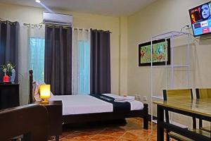 a bedroom with a bed and a tv and a table at Point Vista Transient Accomodation in Daet