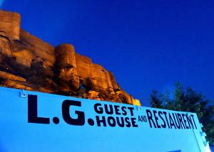 a sign that reads guest house and restaurant next to a mountain at L G Guest House in Jodhpur