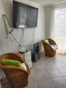 a living room with two chairs and a television on the wall at Casa de Mar in Acapulco