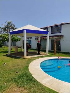 a man standing under a gazebo next to a swimming pool at Casa de Mar in Acapulco