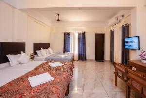 a hotel room with two beds and a flat screen tv at Park View Residency - Guest House Near Sree Padmanabhaswamy Temple in Trivandrum