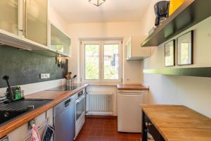a kitchen with white cabinets and a window at Ferienwohnung Aribo in Seeon-Seebruck