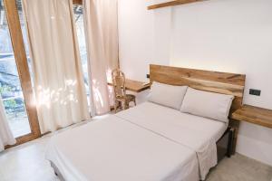 a bedroom with a white bed and a window at Villa Gumamela Siargao in Catangnan