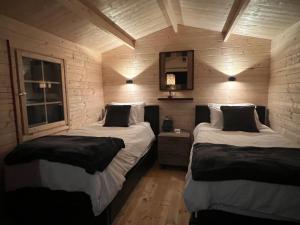 two beds in a room with wooden walls at Creekside Bunkies in Roberts Creek