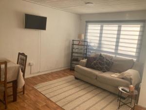 a living room with a couch and a television on the wall at Casas Rabad in Punta Arenas