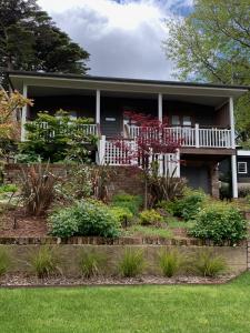 a house with a porch and flowers in the yard at La Casétta in Leura