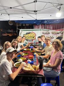 a group of people sitting around a table eating food at Base Seven Hostel in Bandung
