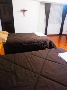 two beds in a room with a cross on the wall at Shekina Huaraz Departament in Huaraz