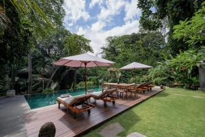 a wooden deck with tables and umbrellas next to a pool at San Michele Villa in Dalung