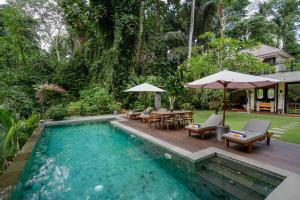a swimming pool in a backyard with a table and chairs at San Michele Villa in Dalung