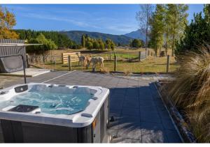 a hot tub on a patio with a horse in a field at Kepler Mountain View in Manapouri +12 photos