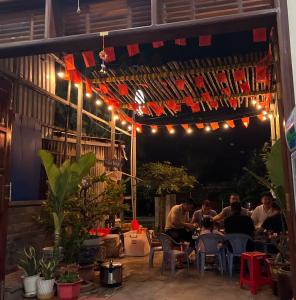 a group of people sitting at tables under a pergola with lights at TRI'S Homestay in Quy Nhon