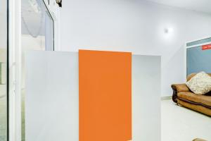 an orange wall in a room with a couch at Hotel O Ratan Pacific Hotel And Party Hall in Ghaziabad