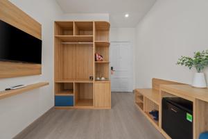 a living room with wooden shelves and a flat screen tv at Vorya Hotel Danang Beach in Danang