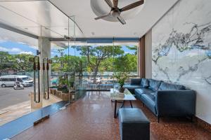 a living room with a blue couch and a large window at Vorya Hotel Danang Beach in Danang
