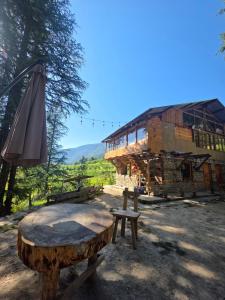 a wooden bench and an umbrella in front of a building at Alex Tribe Cafe and Funstay in Sainj