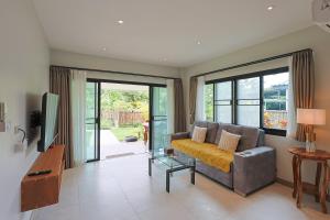 a living room with a couch and a tv at Bang Po Hut Nature - Lush Garden & Natural View in Ban Bang Po