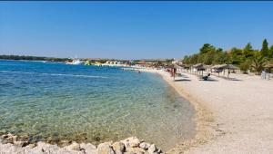 a beach with chairs and umbrellas and the water at Apartmany Vir DaRa in Vir