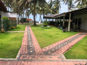 a brick walkway in front of a yard with palm trees at New Romantic Beach Hotel in Toduwawa South