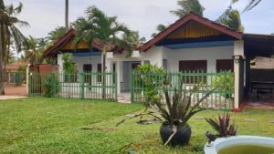 a house with a green fence in a yard at New Romantic Beach Hotel in Toduwawa South